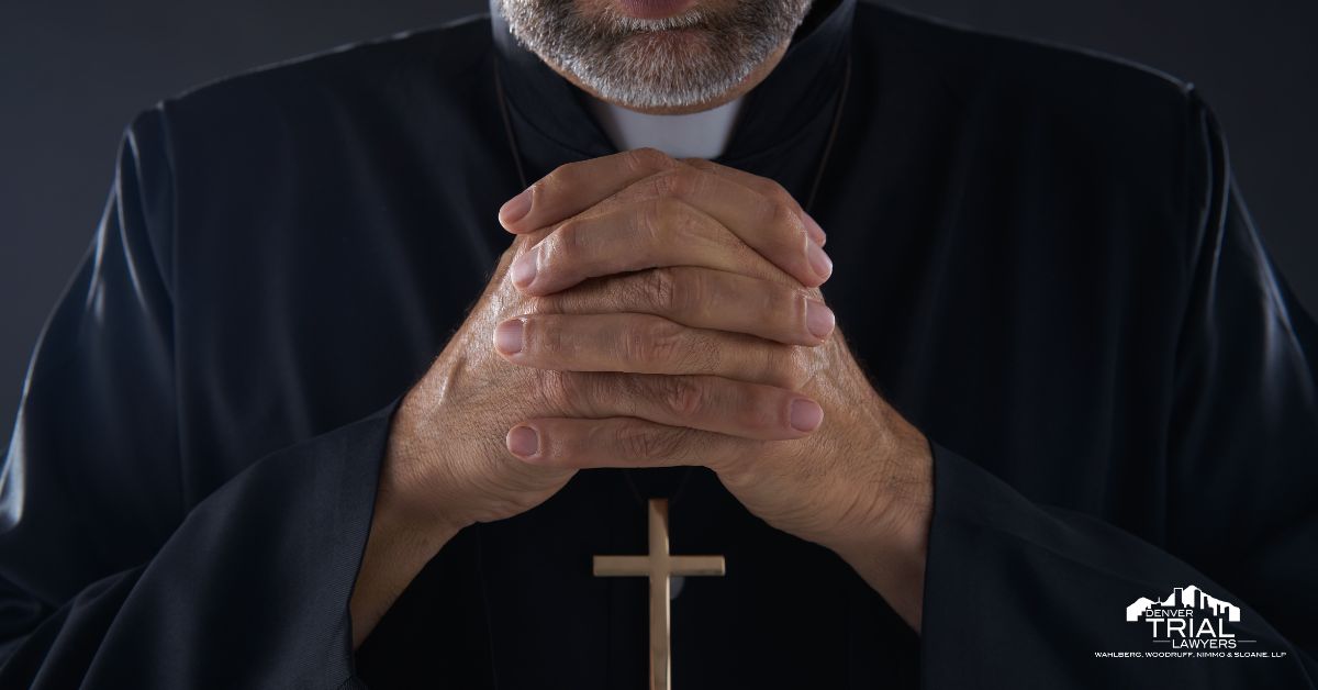 Catholic priest with hands folded and a crucifix around his neck.